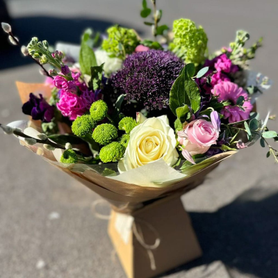 Berry Breeze - A cool-toned hand-tied with purples, pinks, and greens including alliums, carnations, stock, and lilac roses. Rich with texture and colour, perfect for cooler seasons. Berry Breeze - A cool-toned hand-tied with purples, pinks, and greens including alliums, carnations, stock, and lilac roses. Rich with texture and colour, perfect for cooler seasons.